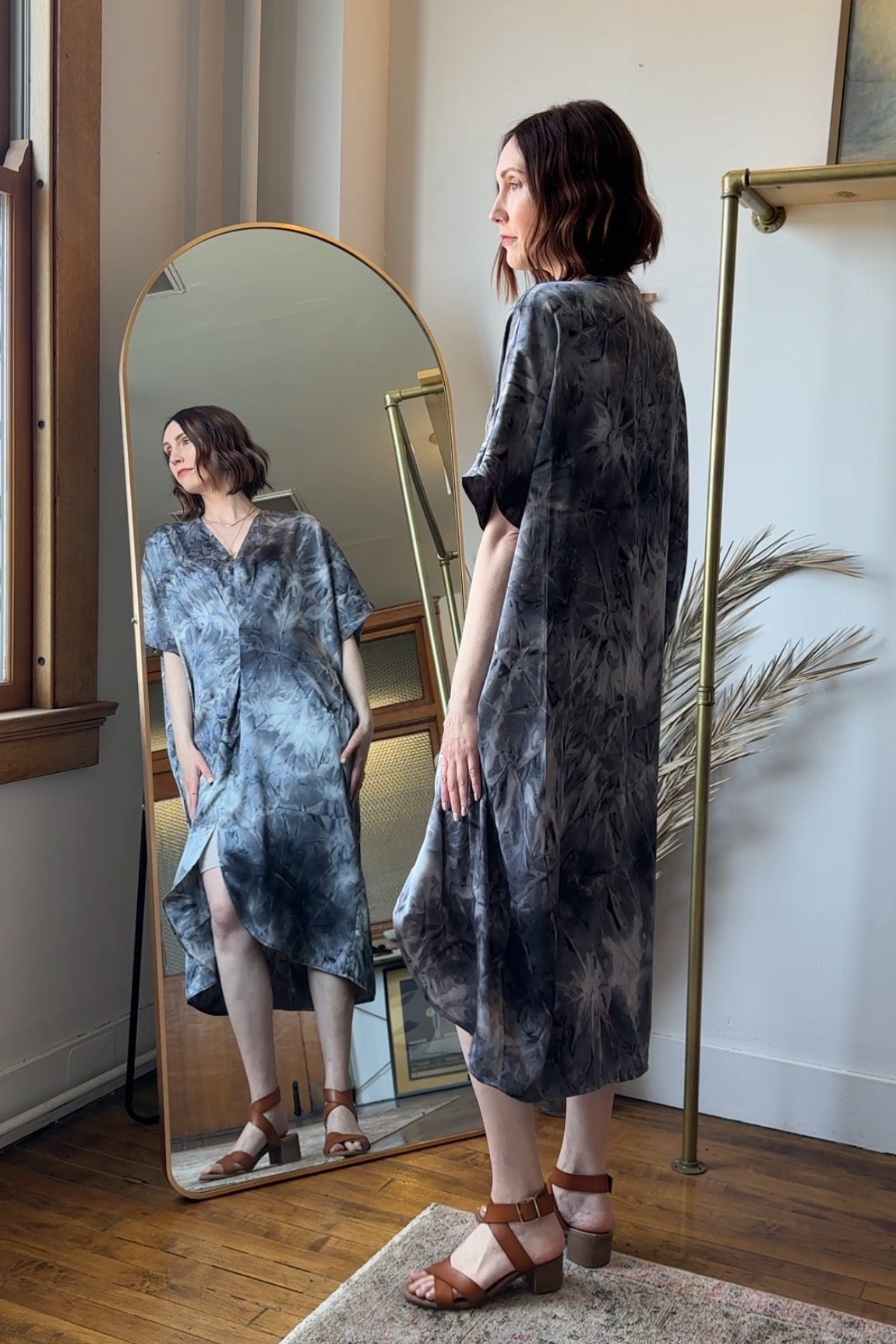 Woman standing in front of a full-length mirror wearing a tie-dye dress.