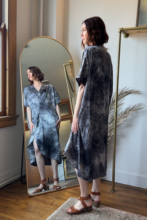 Woman standing in front of a full-length mirror wearing a tie-dye dress.
